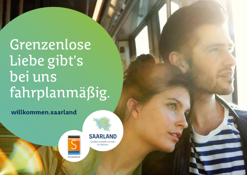 Ein junger Mann und eine Frau schauen aus dem Fenster eines Zuges. Der Text auf Deutsch lautet: "Grenzenlose Liebe gibt's bei uns fahrplanmäßig. willkommen.saarland", mit Logos von Saarland Marketing und Verkehrsbetrieben, die Deutschlands Hidden Champion zeigen.