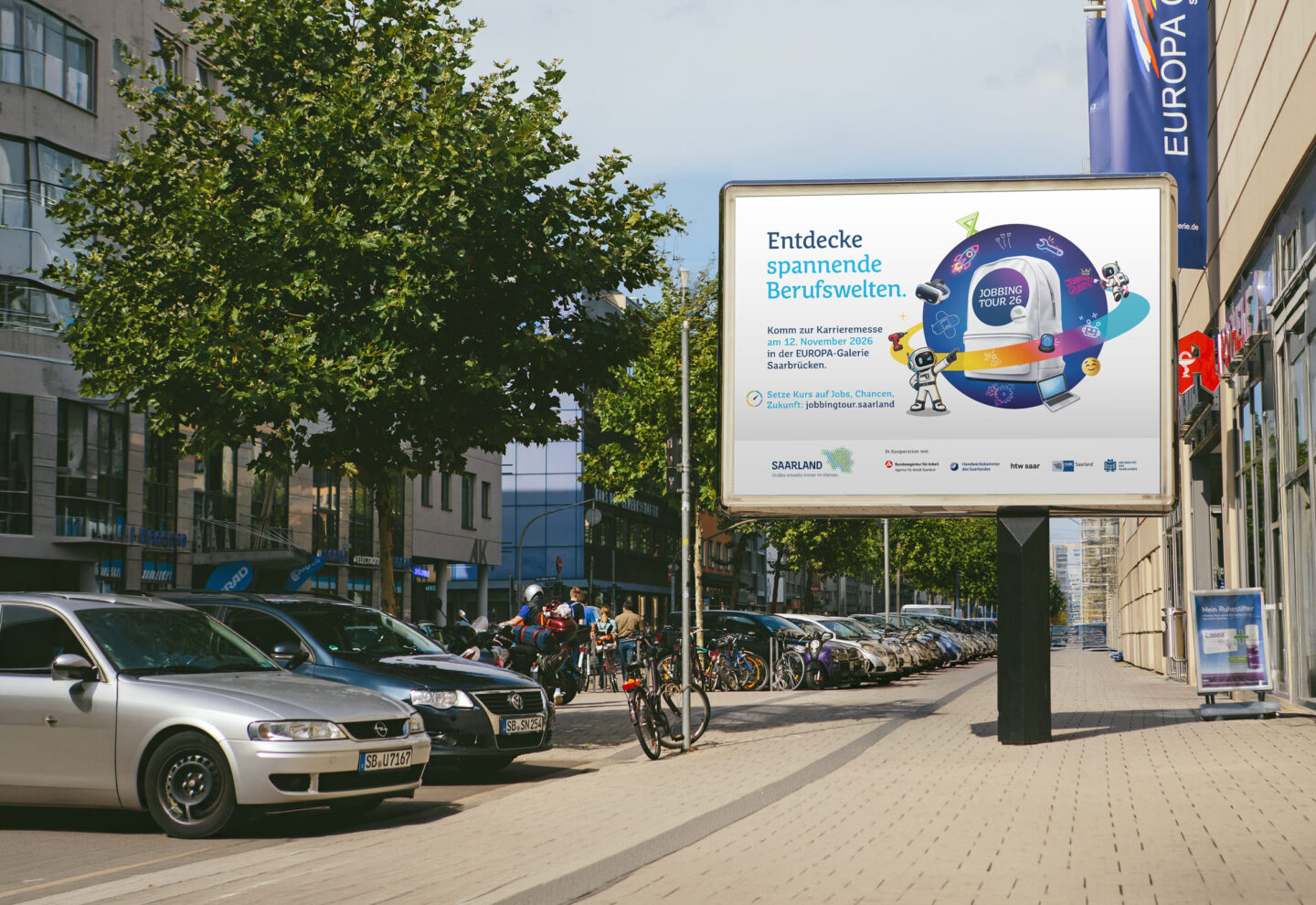 Ein Bürgersteig mit geparkten Autos und einer Werbetafel, auf der eine deutschsprachige Werbung mit einer farbenfrohen Grafik und Text zu sehen ist. Bäume und Gebäude säumen die Straße. Im Hintergrund sind Menschen zu sehen.
